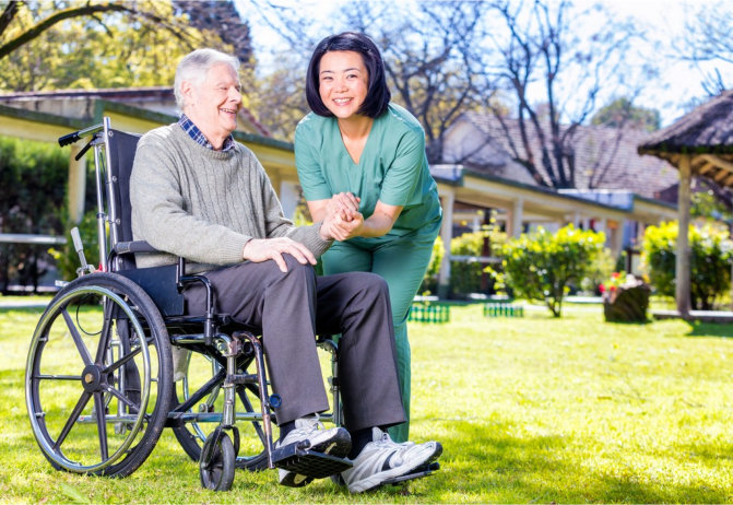 caregiver holding patients hand while on a wheelchair