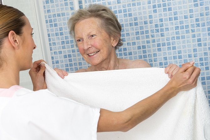 caregiver giving a towel to a elderly woman