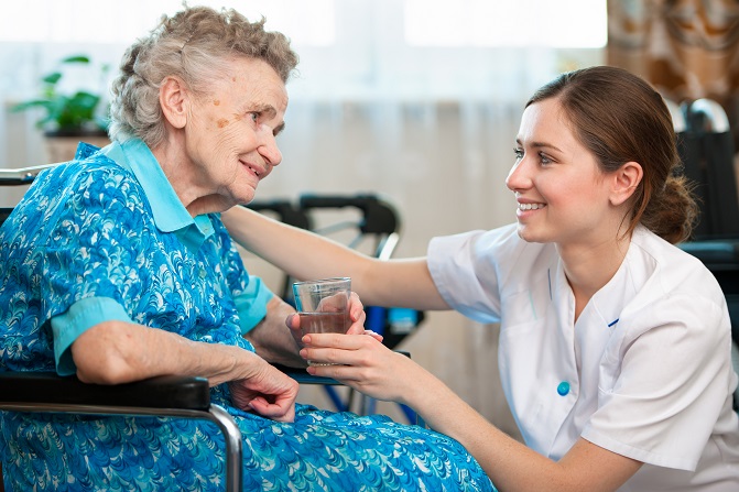 caregiver serving a glass of water to a elderly woman