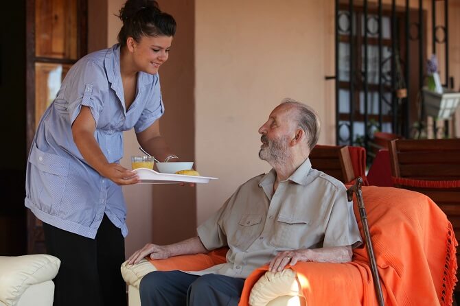 caregiver preparing meals to a elderly man