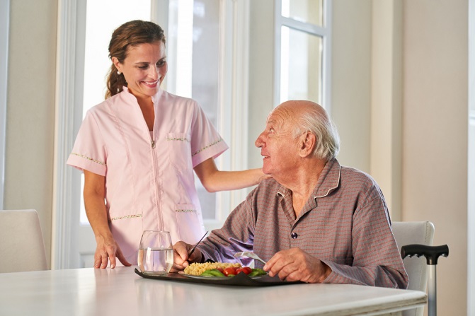 caregiver serving food to a elderly man