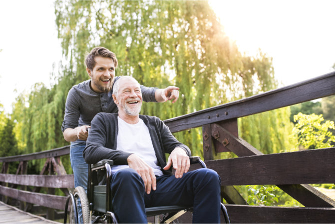smiling elderly man on a wheelchair and a man pointing on their way